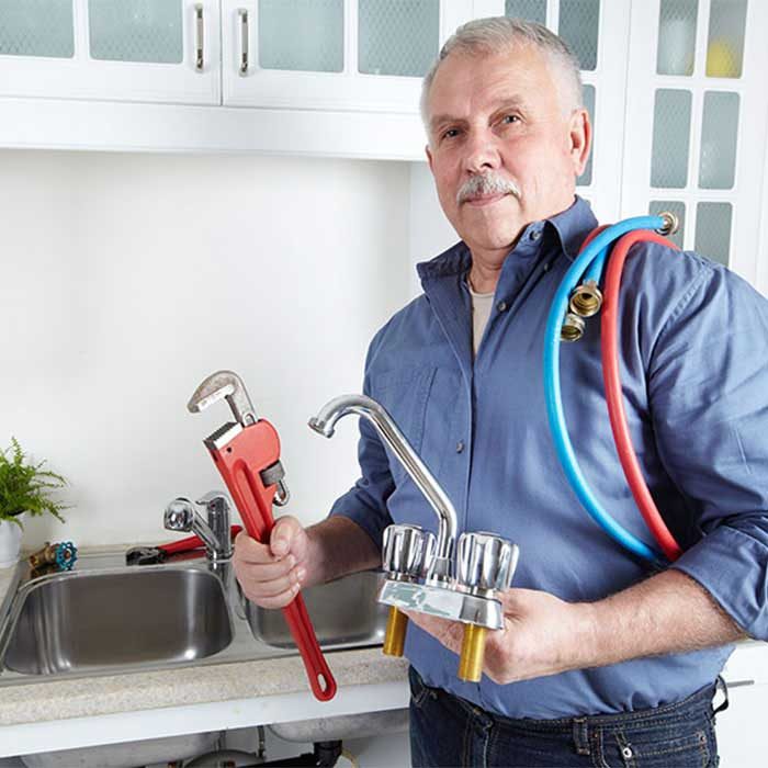 A local plumber holding a wrench and a new tap