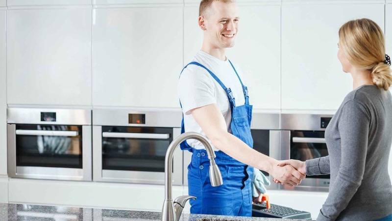 A tradesman shaking hands with a happy customer in her kitchen